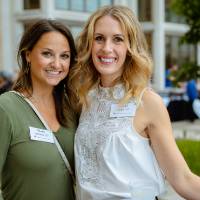 Two guests posing for a photo outside the Alumni Celebration event.